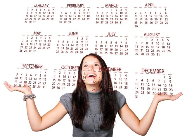 Woman smiling while holding out her hands, with a calendar displaying all twelve months above her.